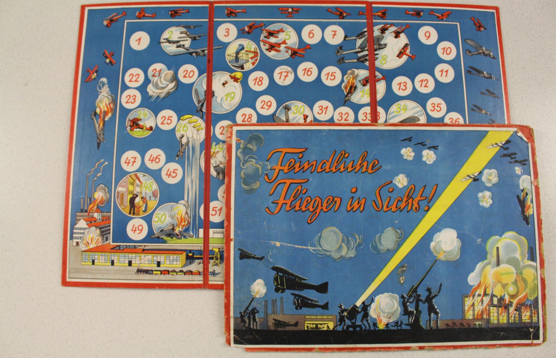 Das Bild zeigt das Brettspiel Feindliche Flieger in Sicht in der Frontalansicht. Ausgebreitet sind ein Spielplan und das Cover. Die Farbgebung der beiden Gegenstände ist hauptsächlich dunkelblau mir einer roten Umramung.