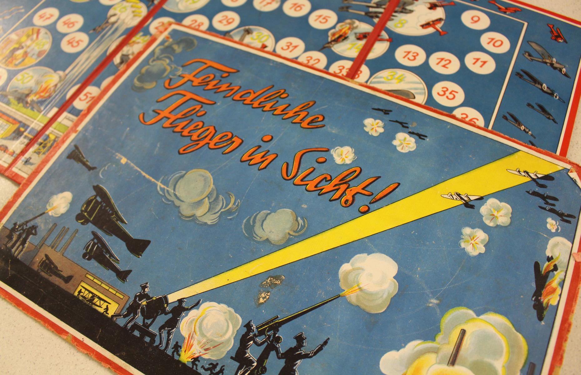 Das Bild zeigt eine Nahaufnahme des Covers. Unter Anderem sind Soldaten an einem Geschütz und ein Strahler zu sehen.