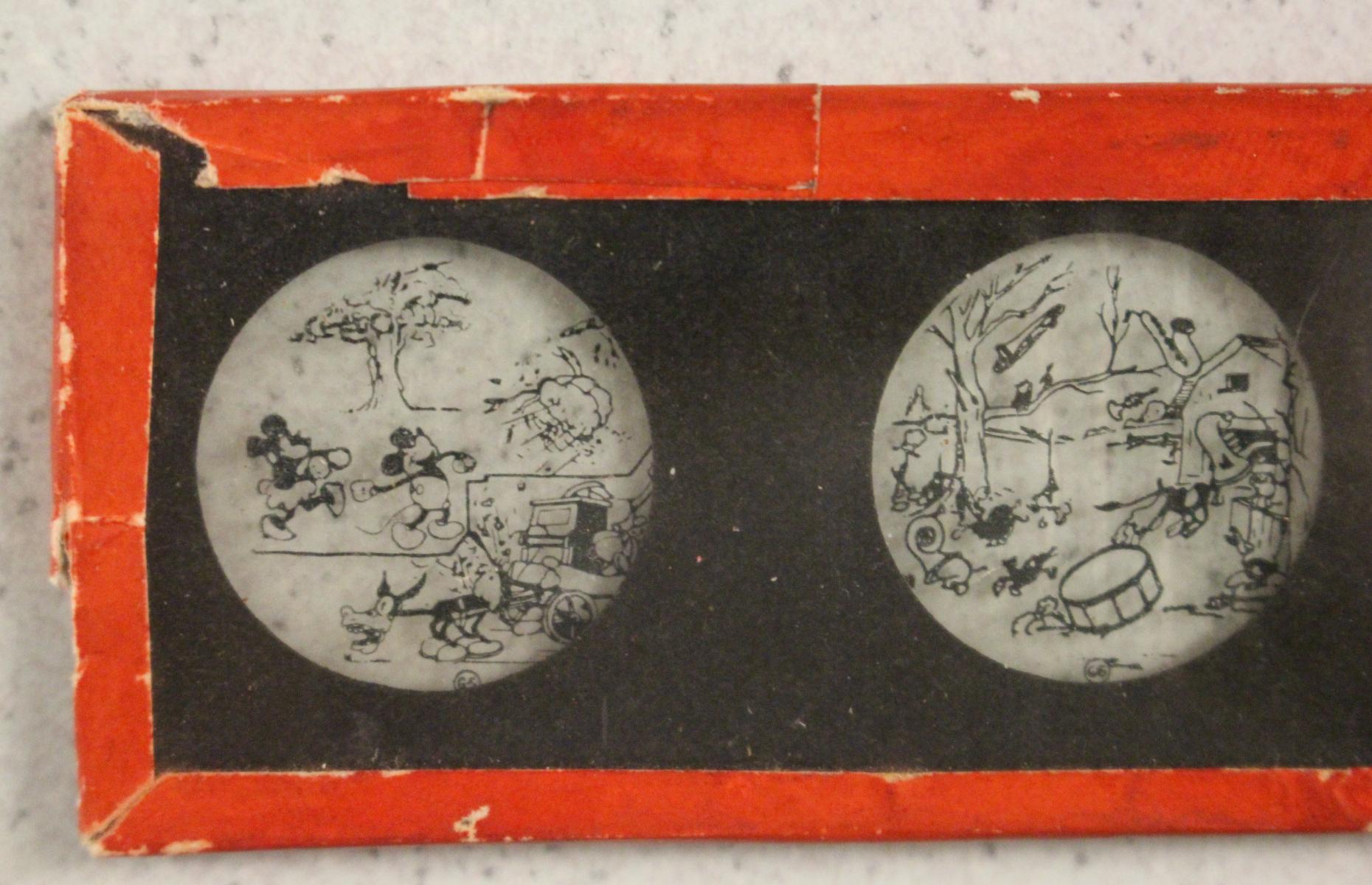 Nahaufnahme einer der Mickey Mouse Glasdurchziehbilder. Die Szene zeigt Mickey und Minnie vor einem Baum.