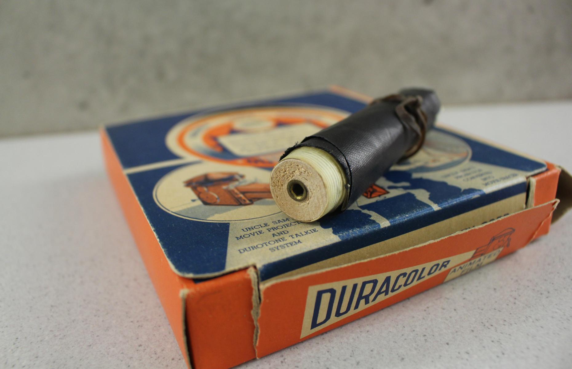 Die Aufbewahrungsschachtel für die Filmrollen der Projektionsapparats mit einer ausgepackten Filmrolle.